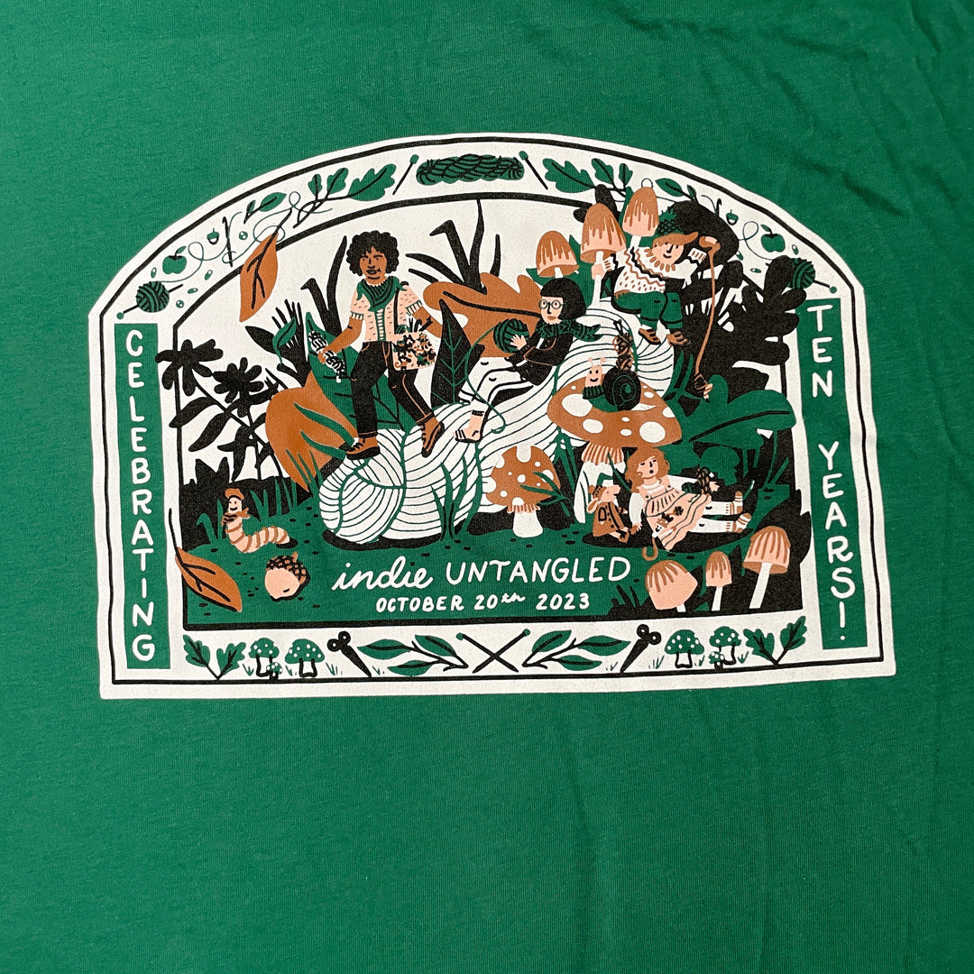 A white, orange and green illustration on a green shirt.