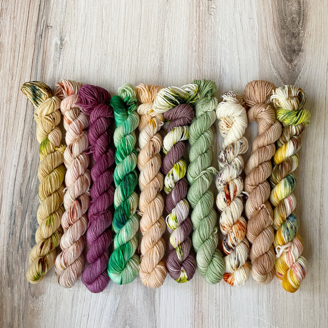 Mini skeins of yarn in shades of green, purple and orange.