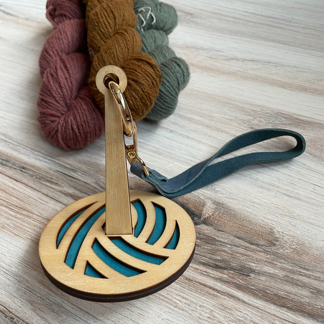 A wooden spool with a blue yarn ball.