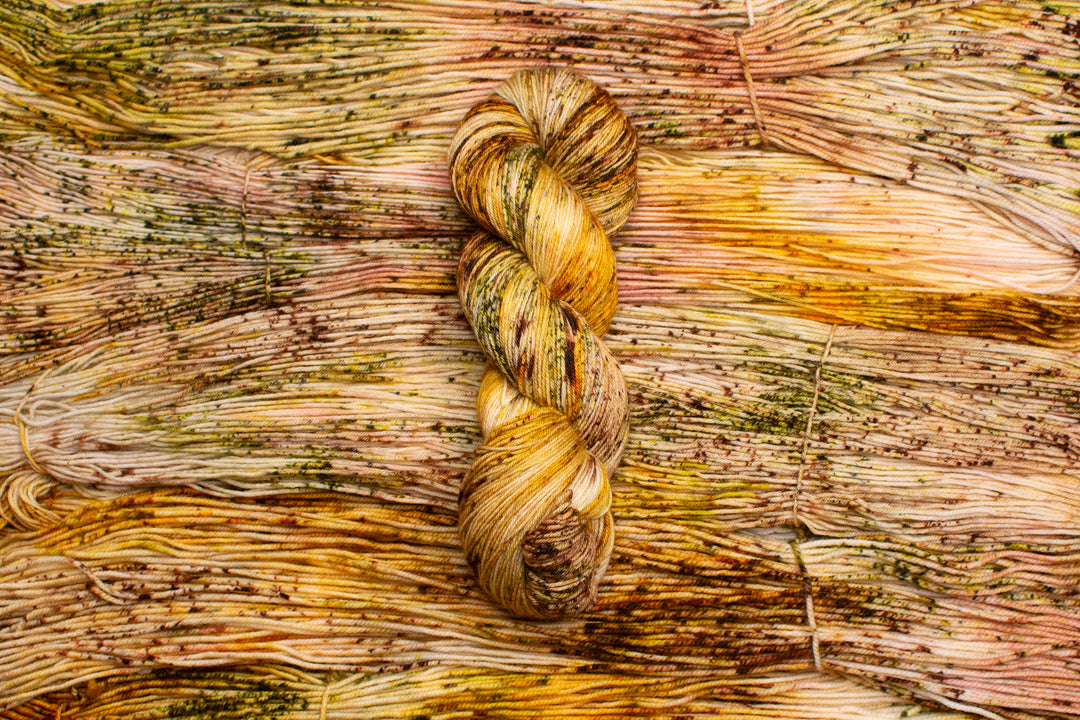 Skeins of yarn in orange, green, brown and gold speckles.
