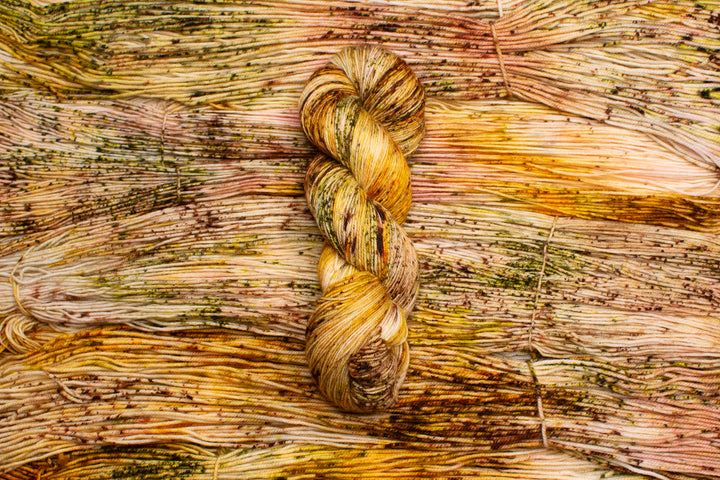 Skeins of yarn in orange, green, brown and gold speckles.