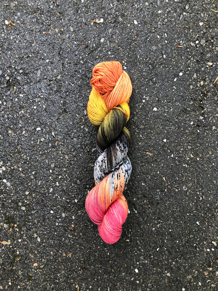 Yarn in shades of orange, yellow, green, black, white, peach and hot pink.