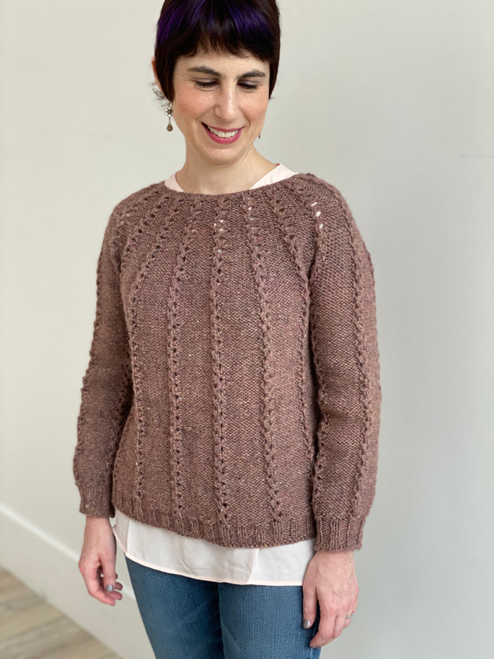 A white woman wears a dusty pink sweater.