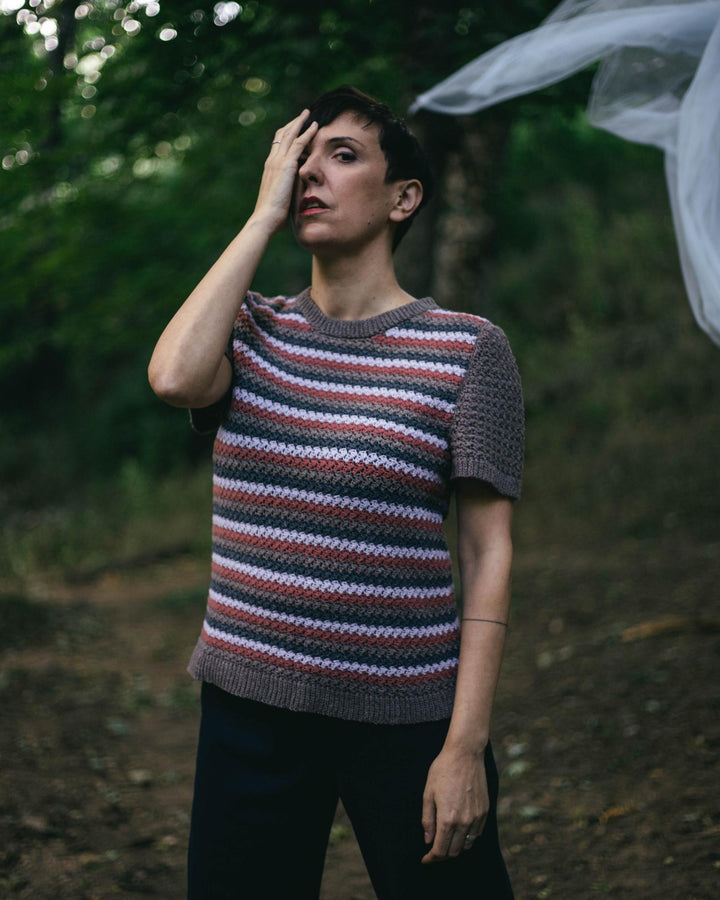 A model wearing a gray, purple and blue crocheted top.