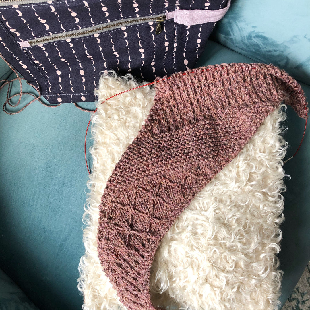 A textured shawl on the needles in a dusty pink.