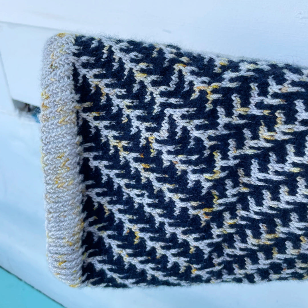 A cowl in dark navy with pine boughs in silver yarn with gold speckles.