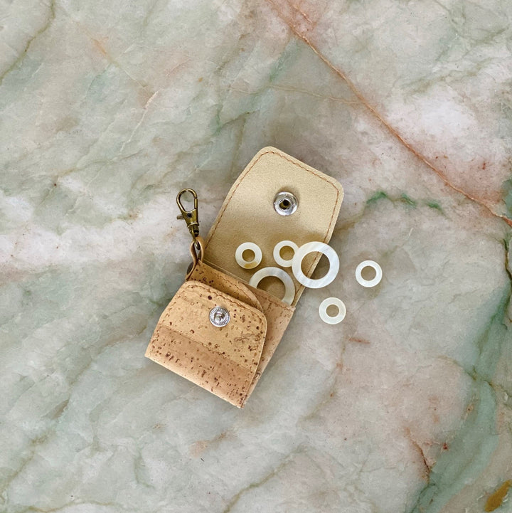 A cork pouch with circular shell stitch markers.