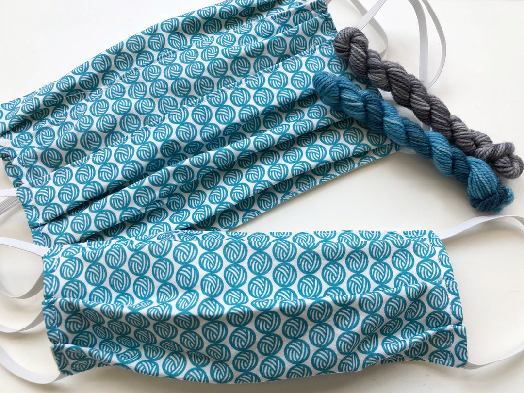 Face masks with teal yarn balls.
