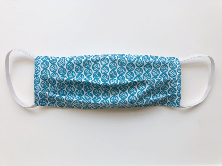 A face mask with teal yarn balls.