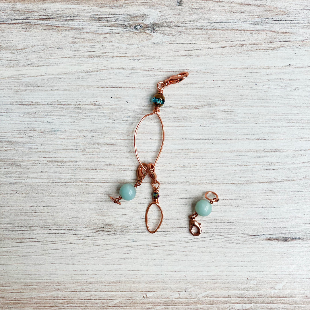 A rose gold zipper pull with aqua semiprecious stones.