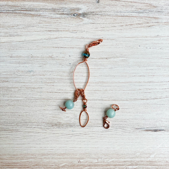 A rose gold zipper pull with aqua semiprecious stones.