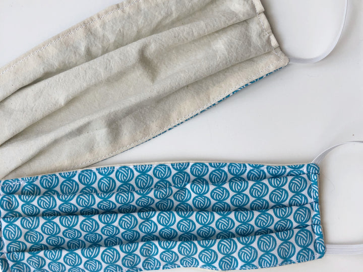 Face masks with teal yarn balls.