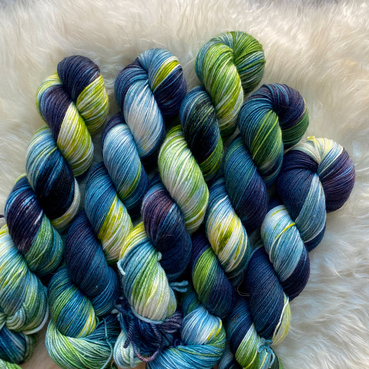 Hand-dyed yarn in deep indigo, vibrant green and bright blue hues.