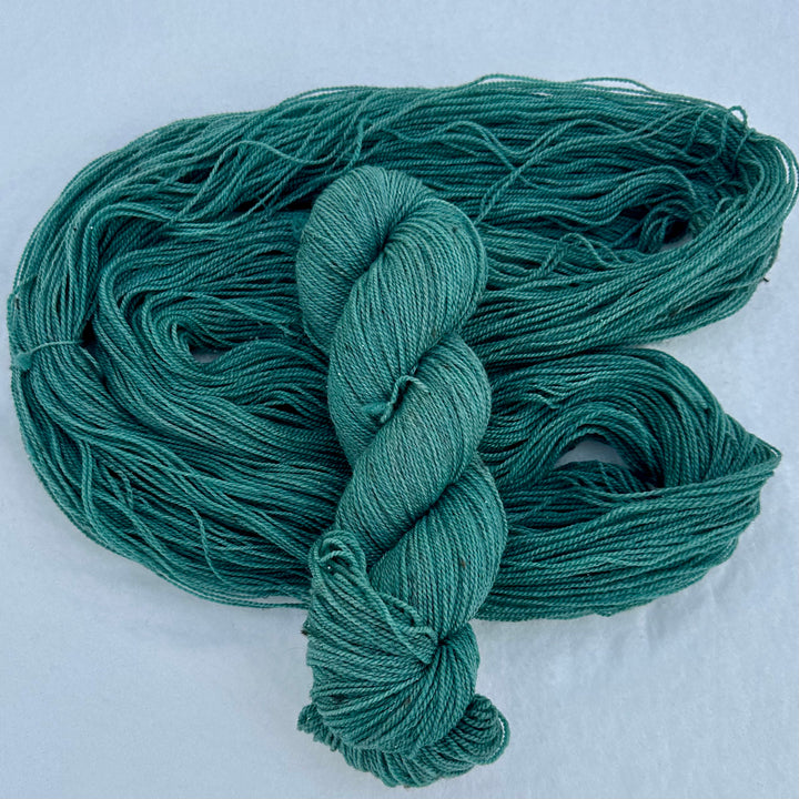 A twisted skein over a loose skein of blue/green yarn.