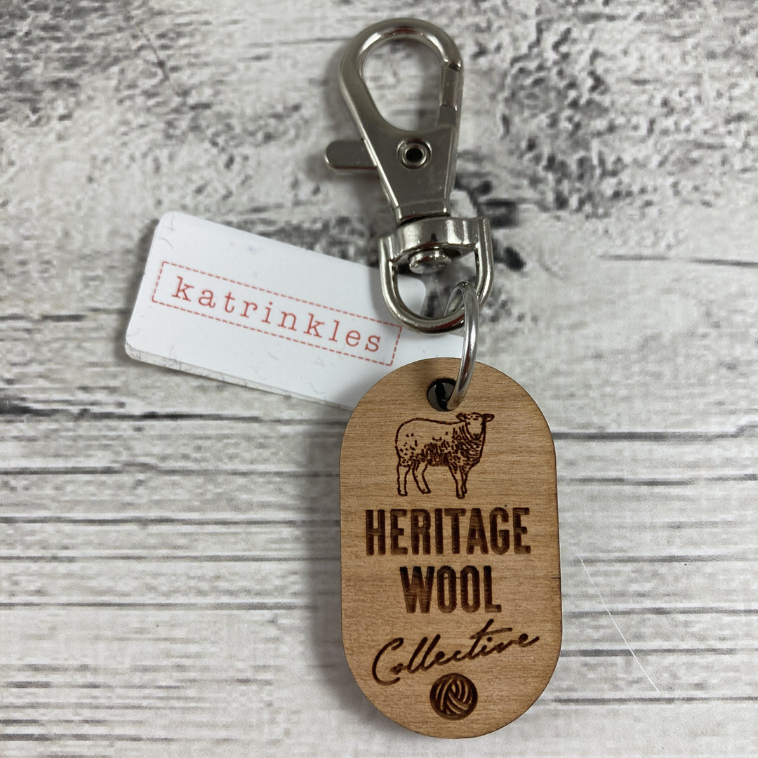 A wooden fob with a sheep and the text Heritage Wool Collective.