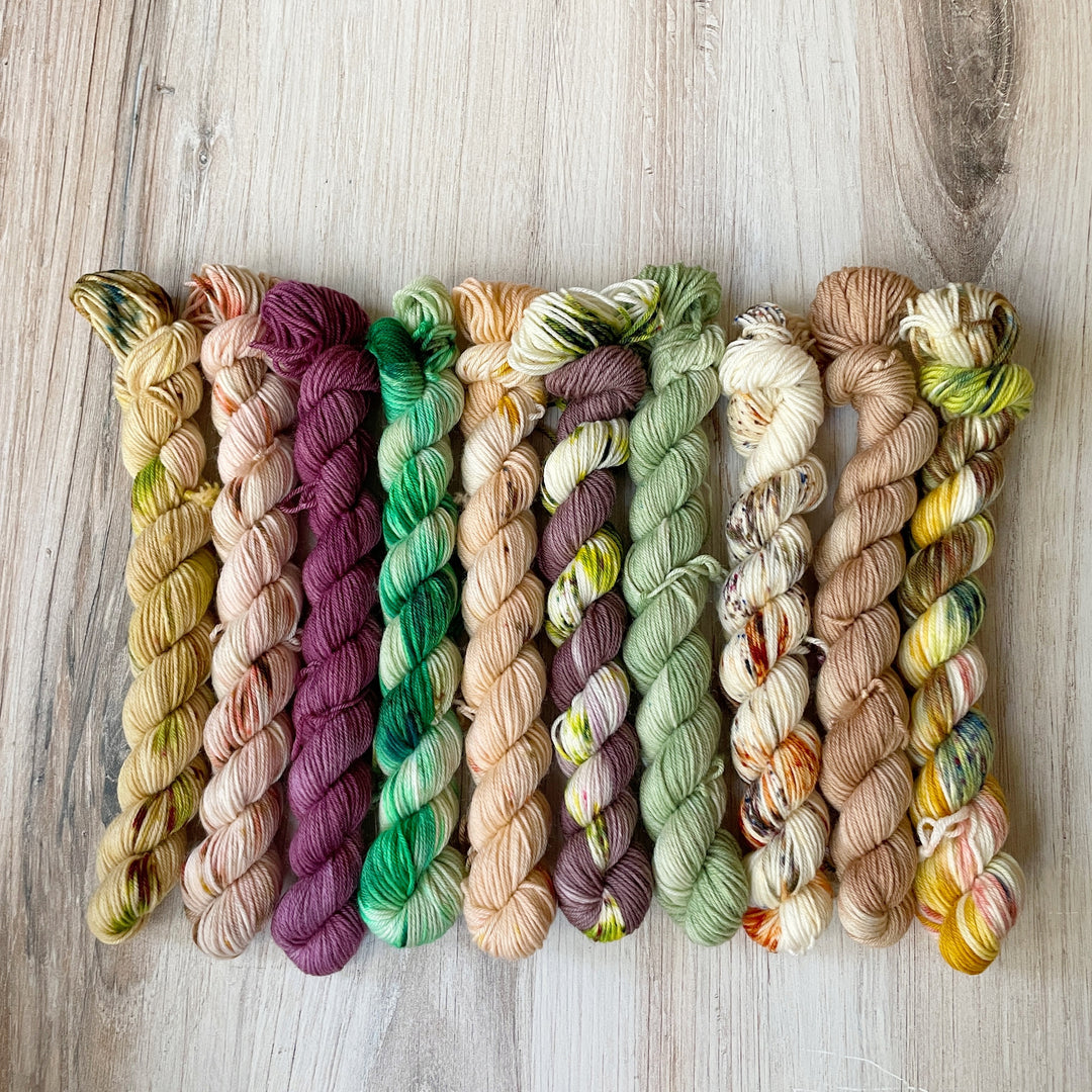 Mini skeins of yarn in shades of green, purple and orange. 