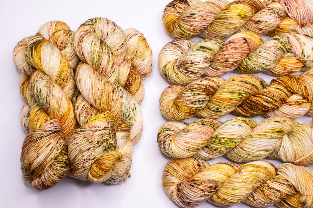 Skeins of yarn in orange, green, brown and gold speckles.