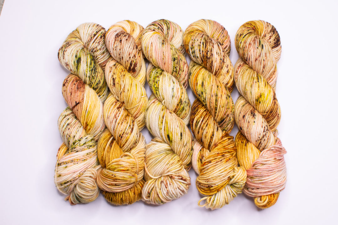 Skeins of yarn in orange, green, brown and gold speckles.