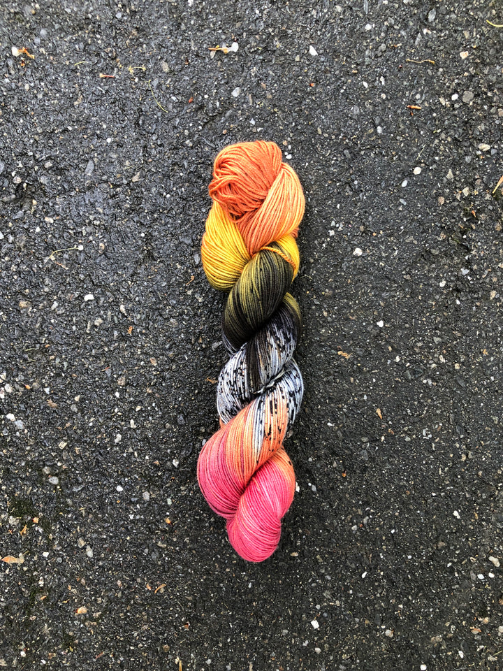 Yarn in shades of orange, yellow, green, black, white, peach and hot pink.