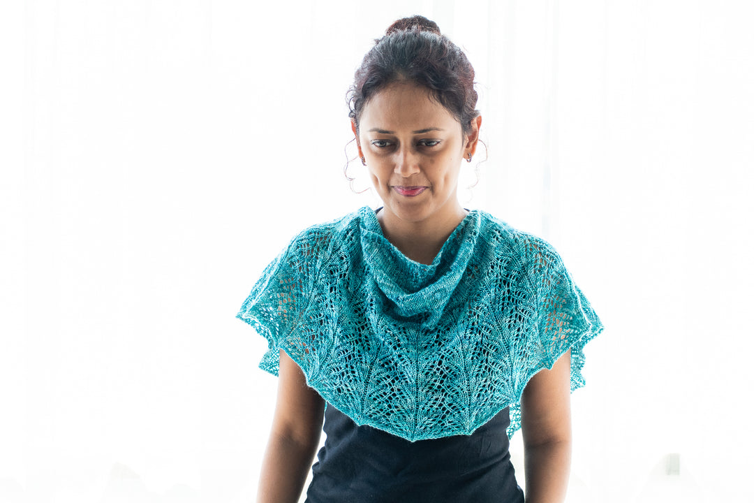 A brown-skinned woman wearing a blue-green lace shawl.