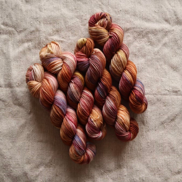 A bundle of skeins in warm, earthy hues.
