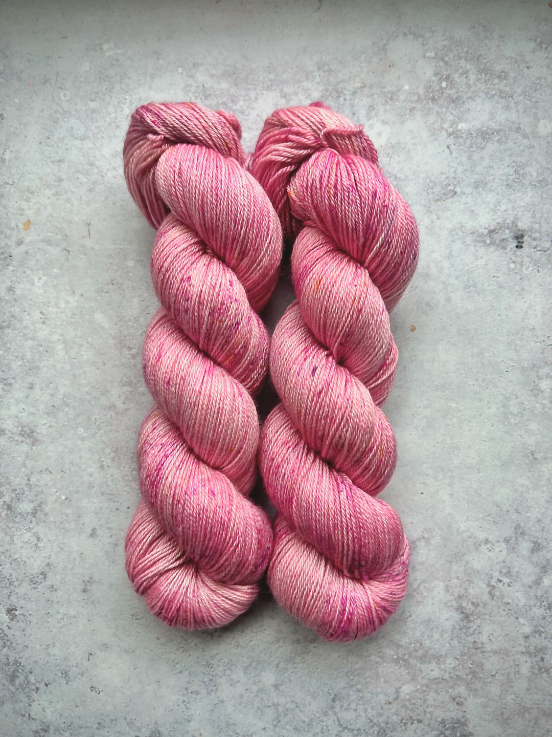 Skeins of pink lightly speckled yarn.