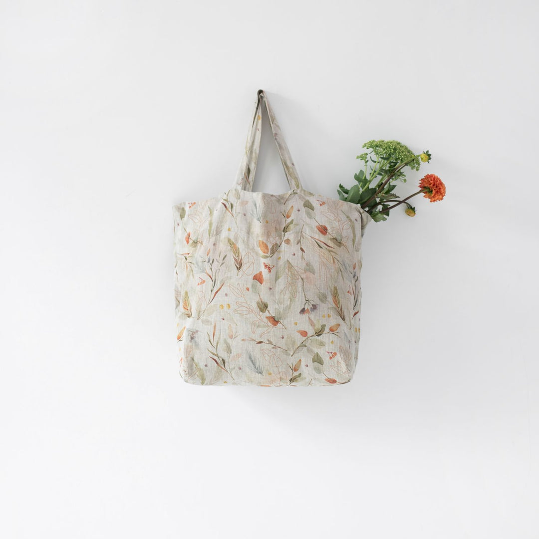A gray tote bag with an orange and green floral print.