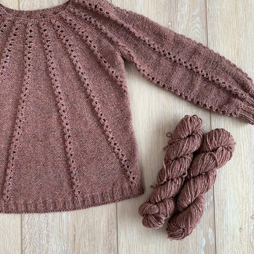 A dusty pink sweater and skeins of dusty pink yarn.