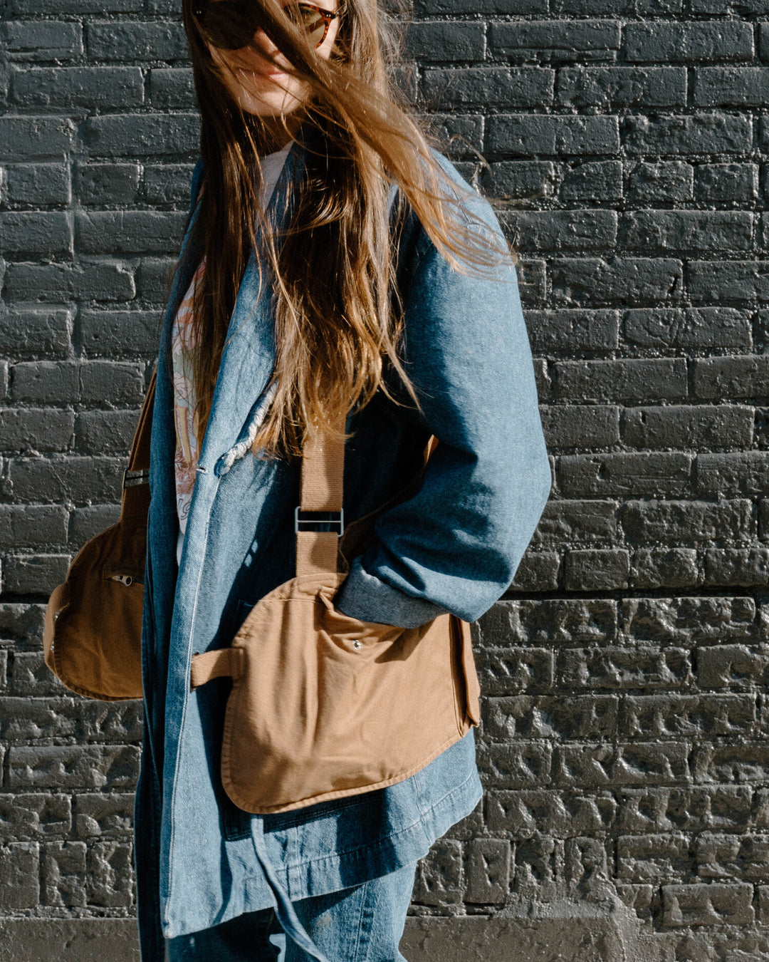 A brown vest with pockets worn over a baggy denim shirt. 
