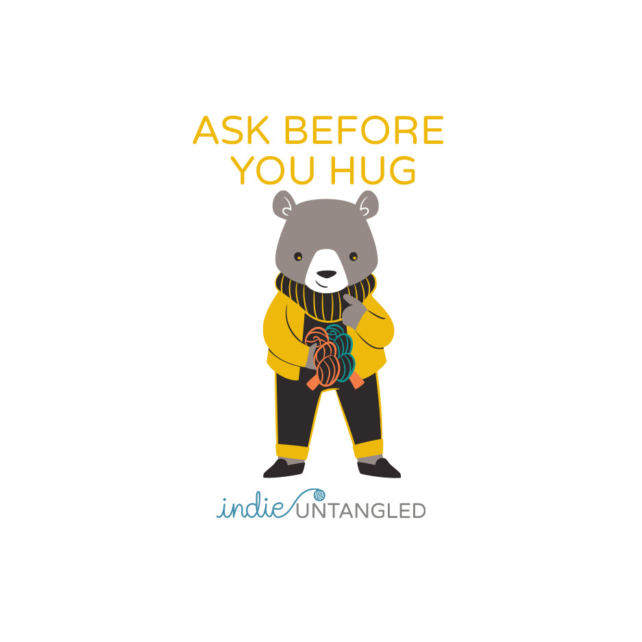 A bear wearing a yellow sweater and the words Ask before you hug.  