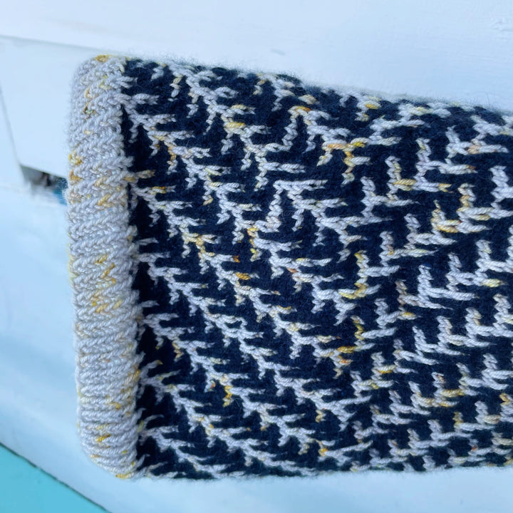A cowl in dark navy with pine boughs in silver yarn with gold speckles.