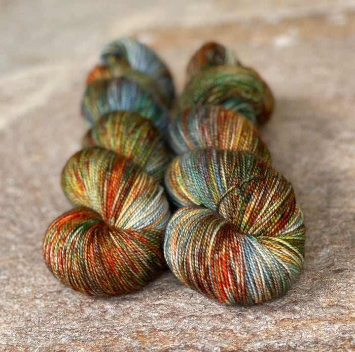 Skeins of yarn with speckles of orange, yellow, green and blue.