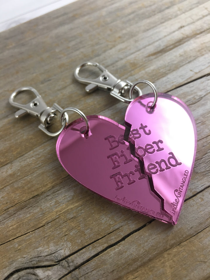 A pink mirrored acrylic heart engraved with the words Best Fiber Friend and the Indie Untangled logo, with silver metal fobs.