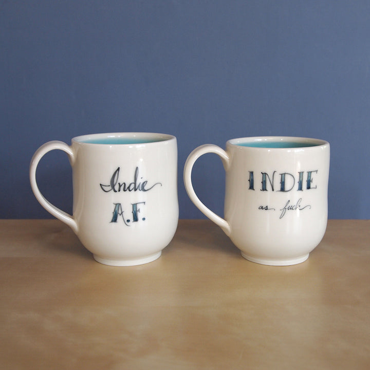 Curved cream mugs with the words Indie AF and INDIE as fuck.