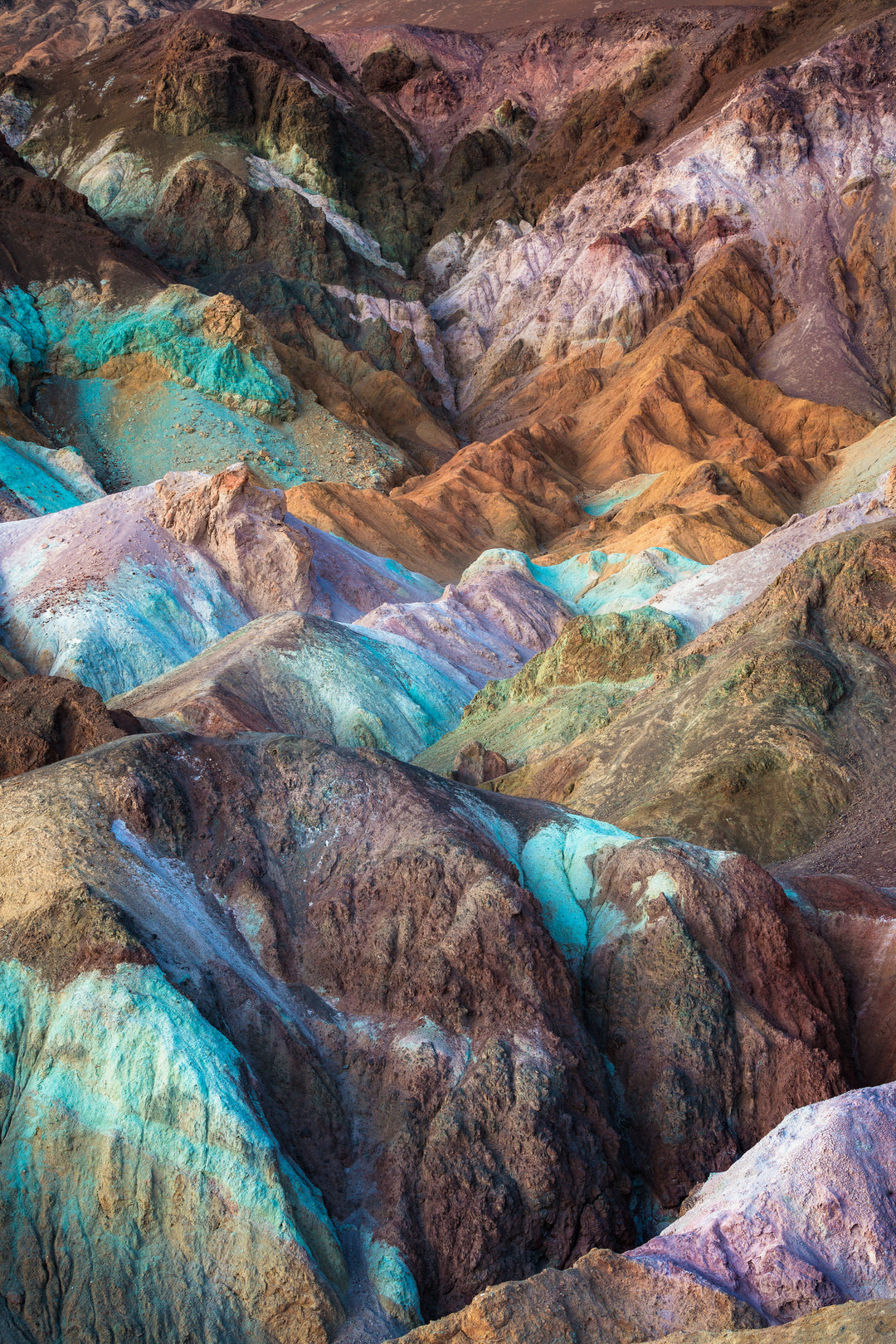 Mountaintops splashed with blue, purple, pink orange and teal colors.