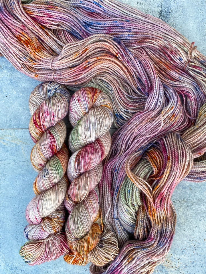 Twisted and loose skeins of pink, green and gold speckled yarn.