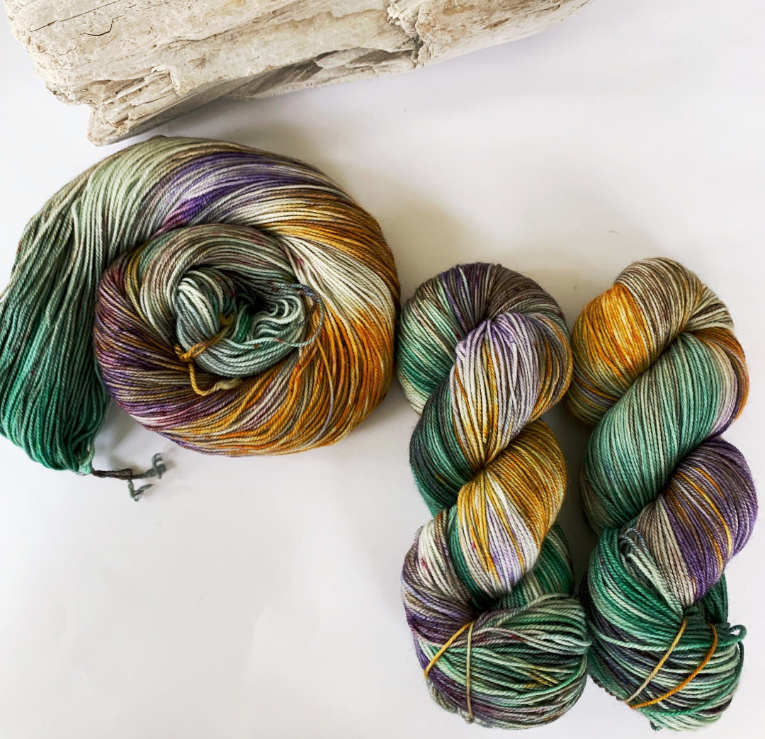 Skeins of green, purple and gold variegated yarn.