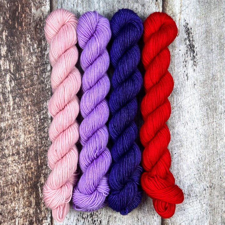 Mini skeins of pale pink, lilac, deep blue and red yarn.