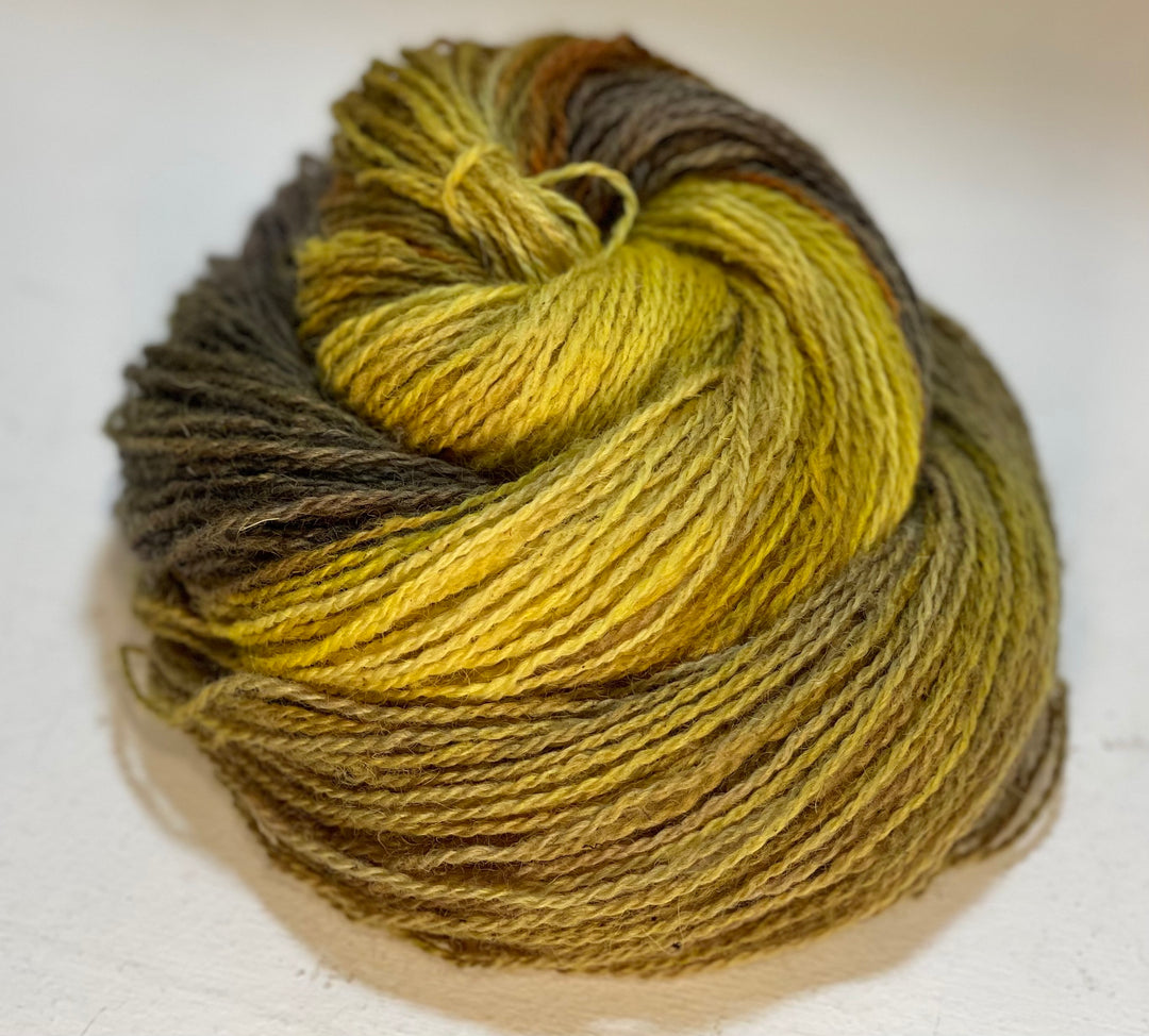 A coiled skein of yarn in yellow, orange, purple and gray.