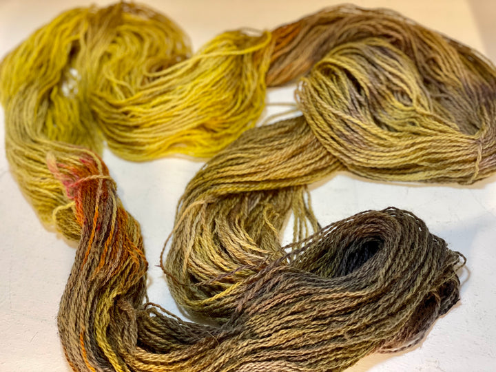 A loose skein of yarn in yellow, orange, purple and gray.