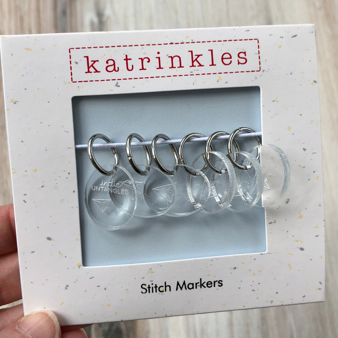 A package of clear acrylic stitch markers with the words Indie Untangled and an illustration of a paper airplane.