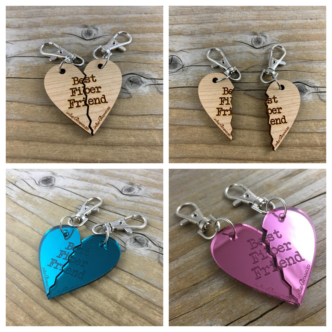 Pink and teal mirrored acrylic and wooden hearts engraved with the words Best Fiber Friend and the Indie Untangled logo, with silver metal fobs.