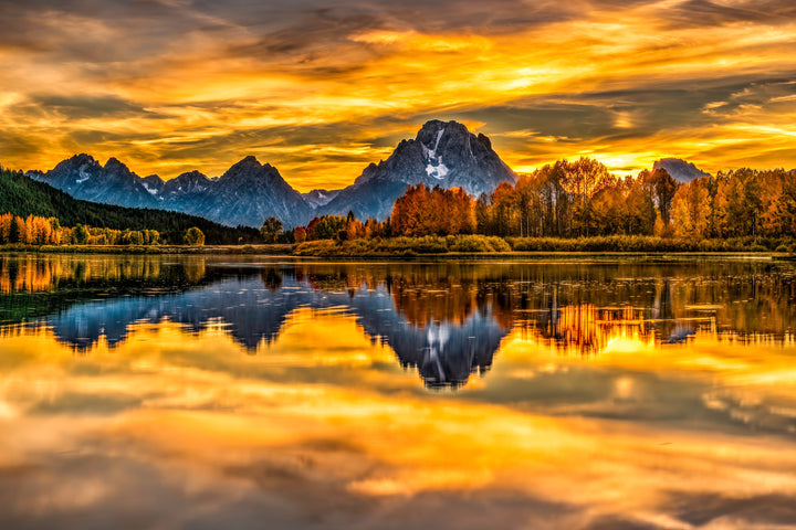 Yellow and orange foliage surrounding a mountain, which is reflected in a lake.
