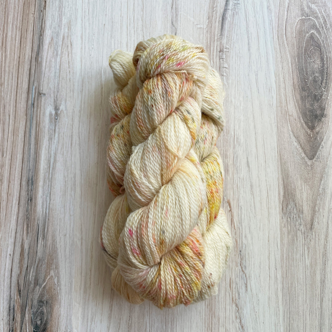 Cream yarn speckled with red and gold.