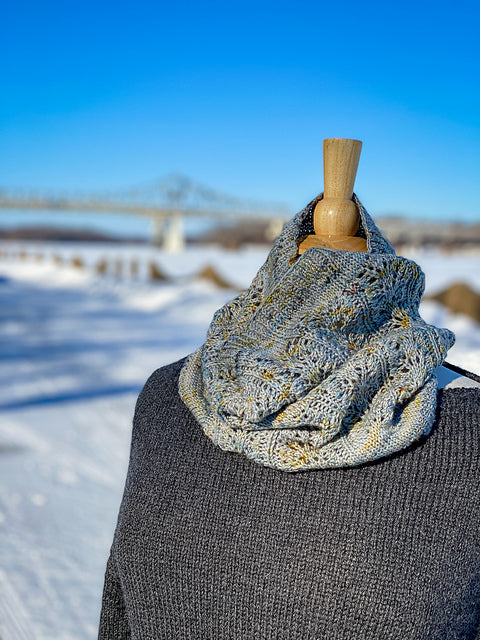 A blue and gold speckled cowl on a dress form in a snowy landscape. 