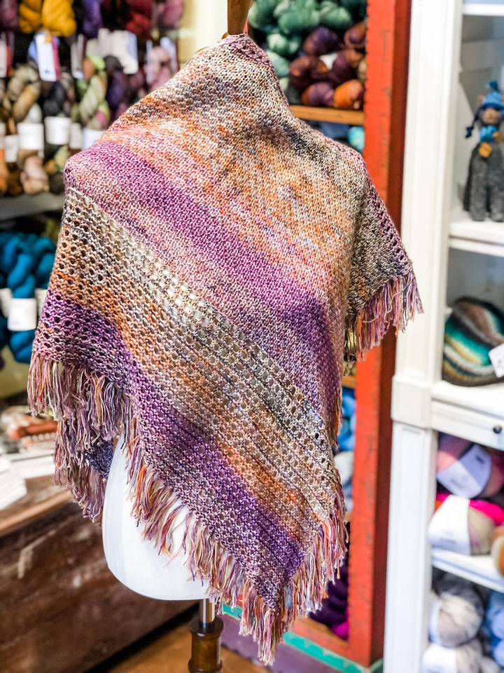 A purple, gray and orange shawl with eyelets and textured stitches on a dress form. 