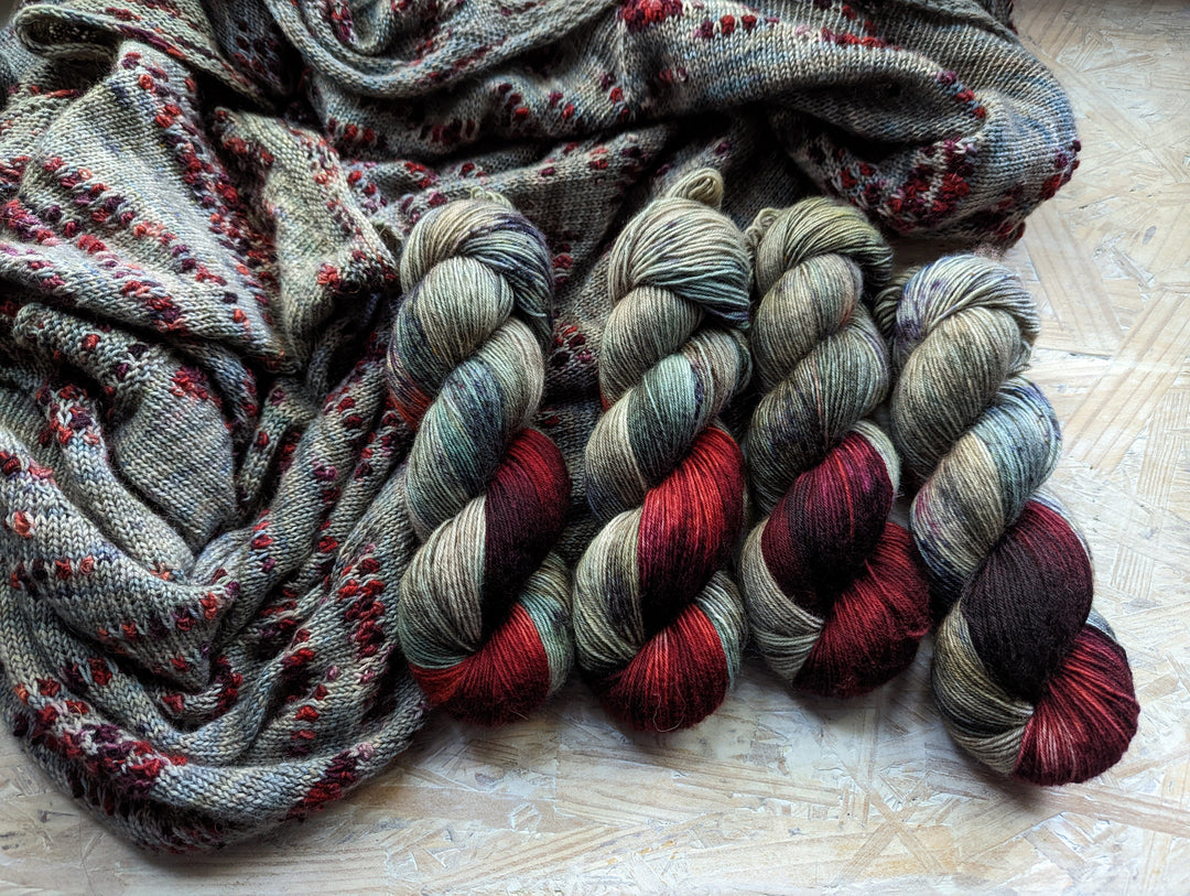 Gray-blue yarn and knitting with bands of red and purple.