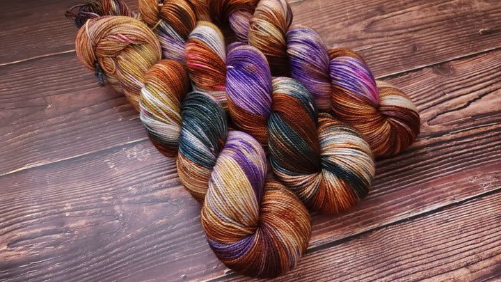 Hand-dyed yarn in purple, brown, green and gold.