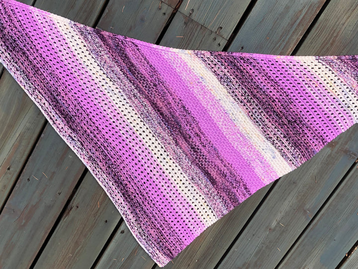 A textured and eyelet shawl in shades of pink, purple and white.