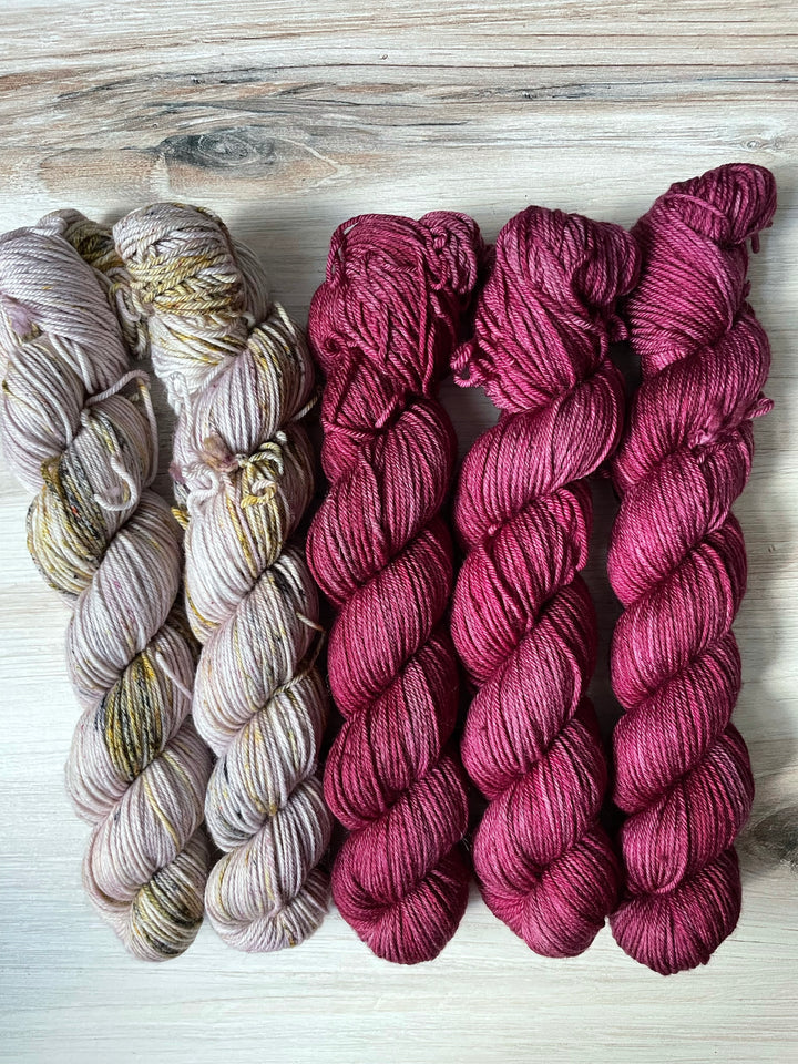 Skeins of gray yarn with gold speckles and skeins of purple yarn 